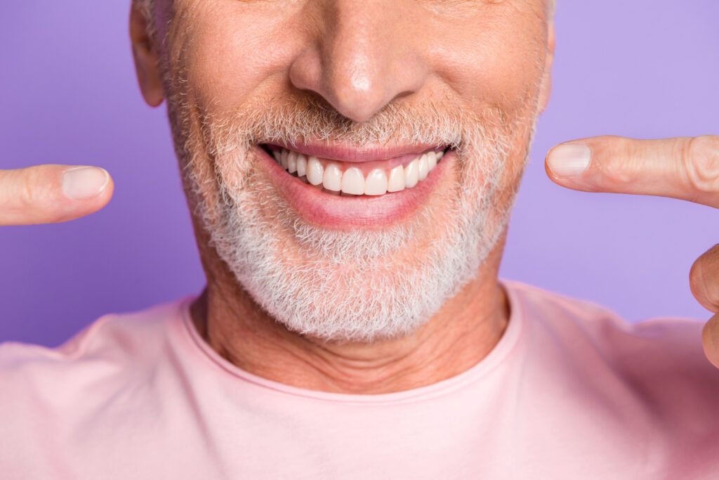 Older male pointing to his healthy smile