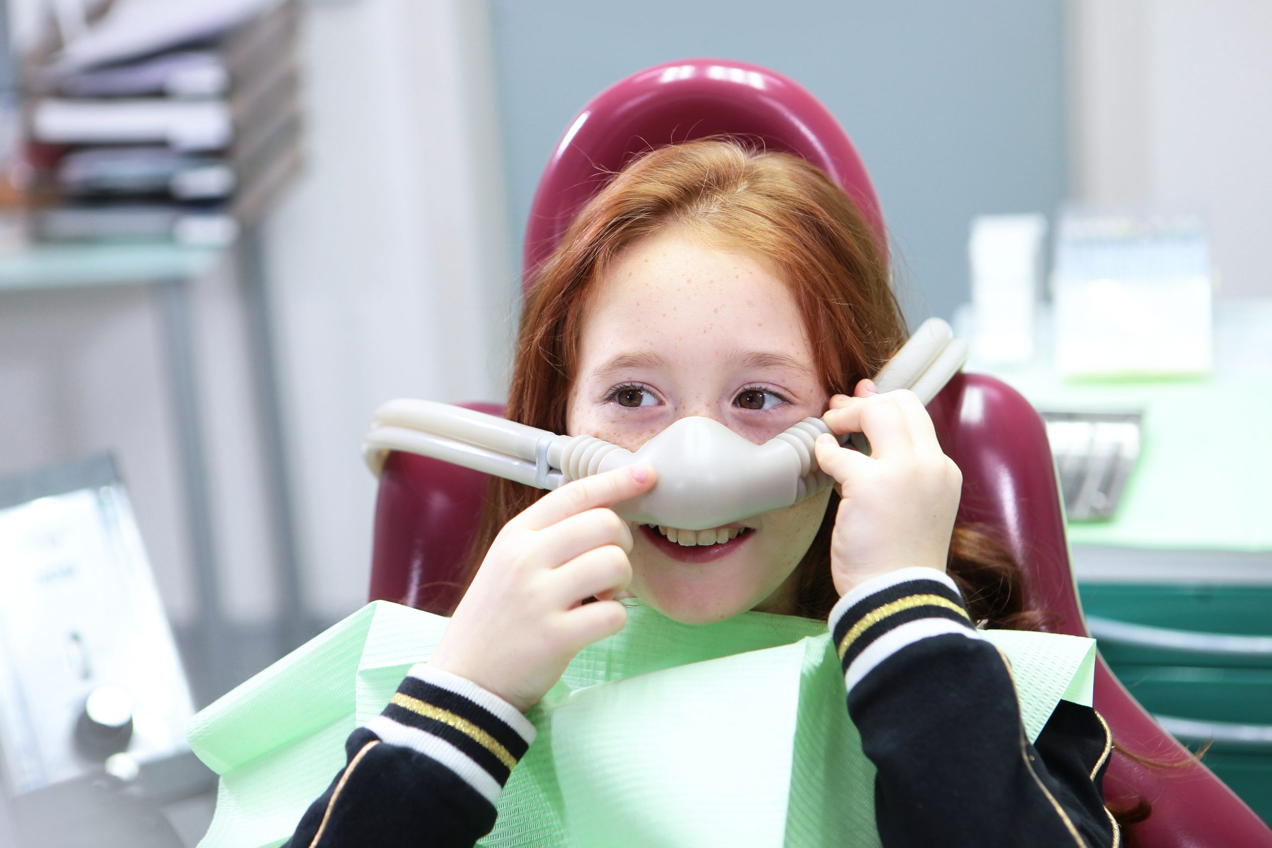 Little girl with sedation mask. Treatment of children's teeth with nitrous oxide. Anesthesia for children in dental treatment. Children's dentistry.