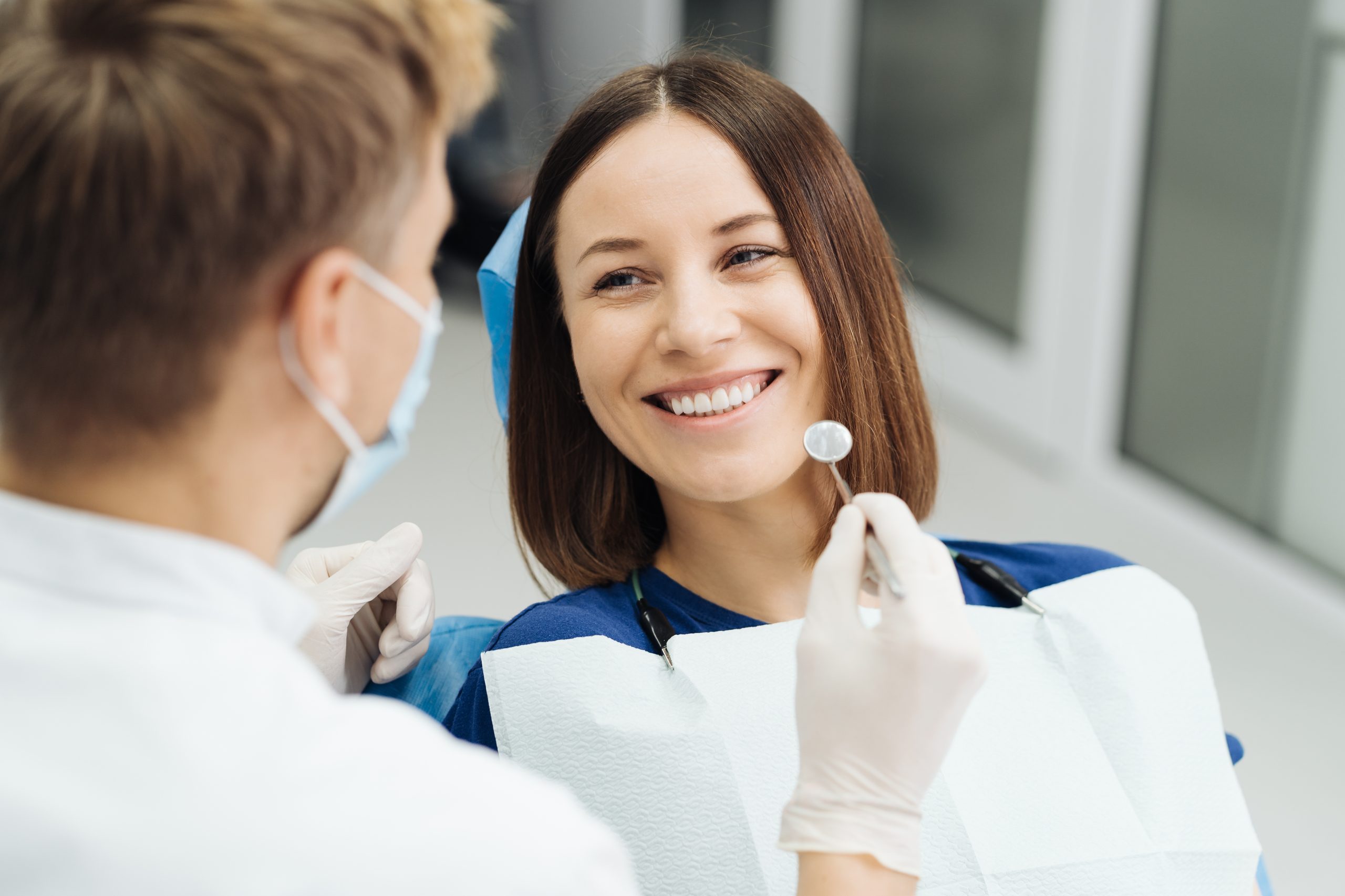 Smiling woman receiving a dental examination from a masked dentist.